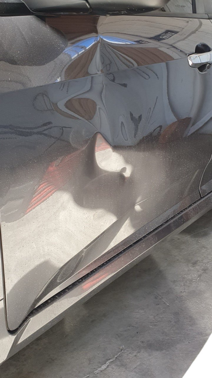 Detalhe de painel de carro com reparo de martelinho de ouro finalizado, sem marca do amassado