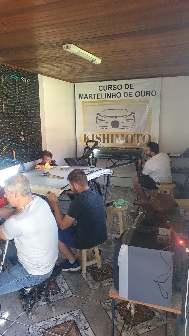 Turma do curso praticando martelinho de ouro numa porta de carro, dentro da oficina Kishimoto